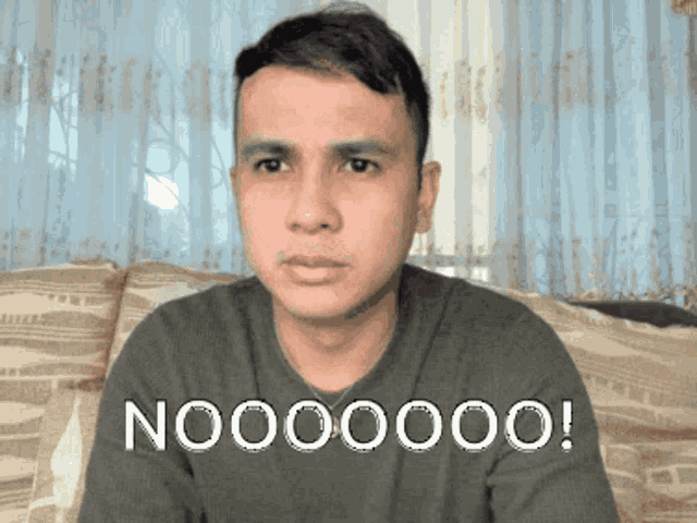 a man is sitting on a couch with the word nooo on his face