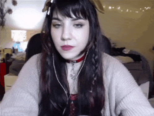 a woman wearing headphones and a choker looks at the camera with a serious look on her face