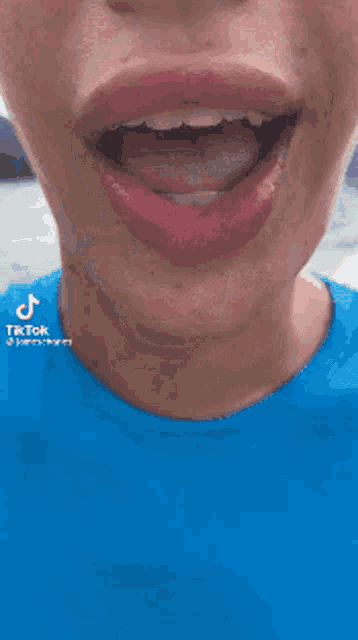a close up of a person 's face with their mouth open and a blue shirt on .