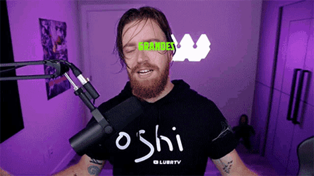 a man with a beard is wearing a black shirt that says oshi