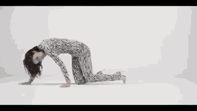 a woman is kneeling on the floor wearing a zebra print bodysuit .