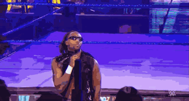 a wrestler stands in a wrestling ring with a microphone