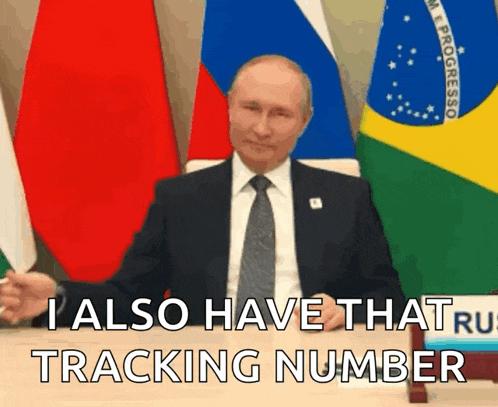 a man in a suit and tie is sitting at a table with flags in the background and says i also have that tracking number