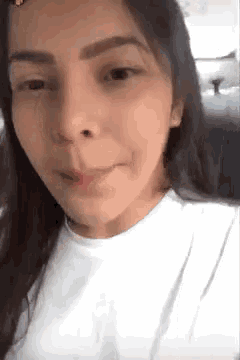 a close up of a woman 's face in a car . she is wearing a white shirt and smiling .