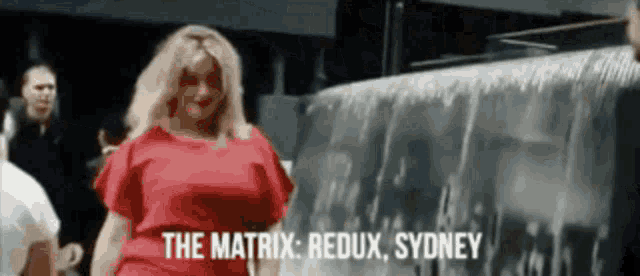 a woman in a red dress is standing in front of a waterfall and says the matrix redux sydney