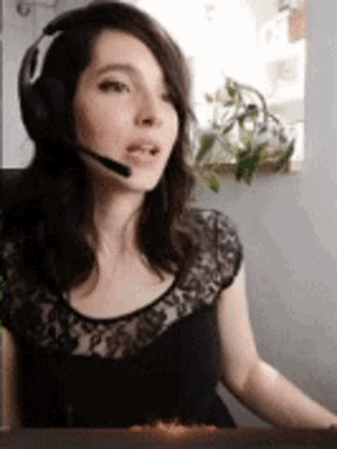 a woman wearing headphones and a headset is sitting at a desk .