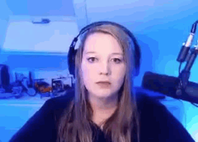 a woman wearing headphones is sitting in front of a microphone in a room .
