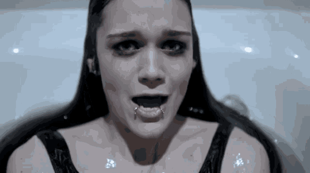 a woman in a bathtub with her mouth open and piercings in her teeth