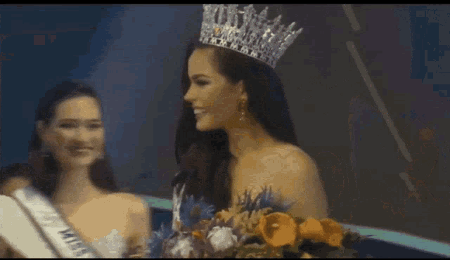 a woman wearing a crown and a miss universe sash smiles