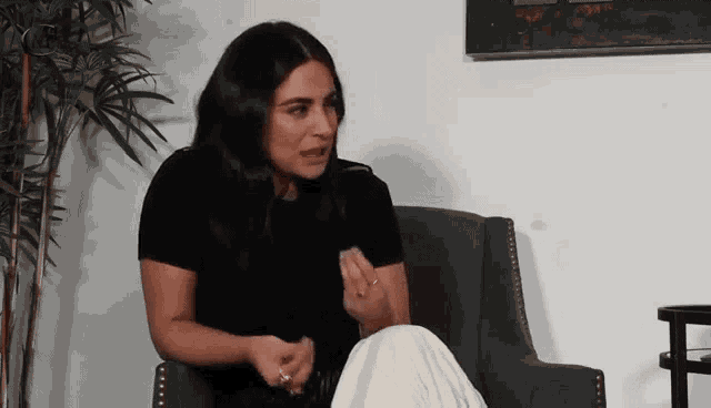 a woman is sitting in a chair with her legs crossed and talking .