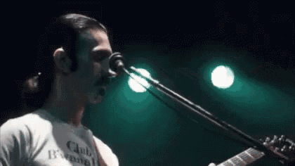 a man is playing a guitar and singing into a microphone on a stage .