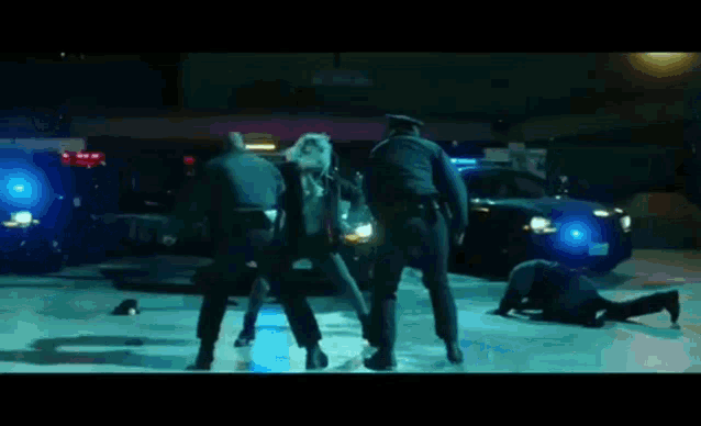 a group of police officers are standing around a man laying on the ground .