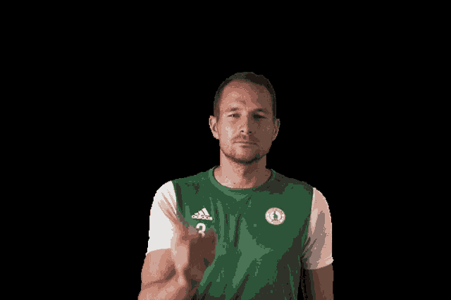 a man wearing a green shirt with a white circle on it is pointing at something