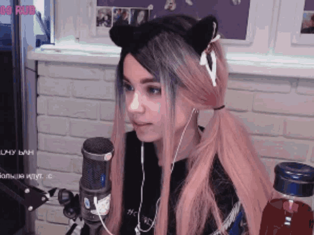 a girl wearing a cat ear headband is sitting in front of a microphone and a bottle of red liquid
