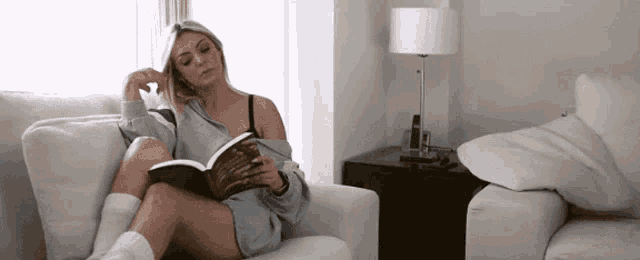 a woman is sitting in a chair reading a book