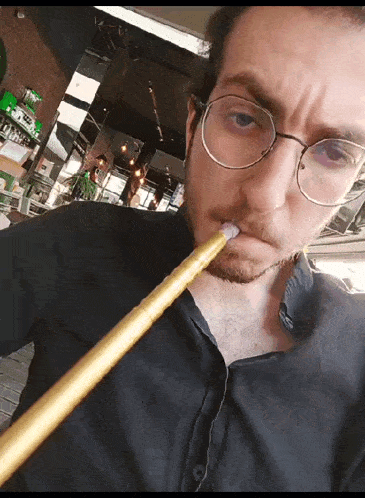a man wearing glasses smoking a hookah in a restaurant