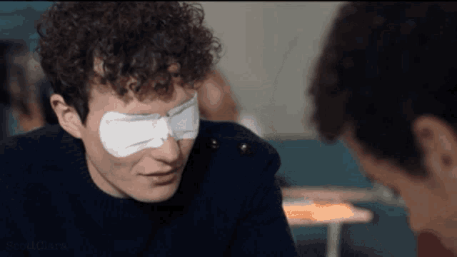 a man with a bandage on his eye is looking at another man