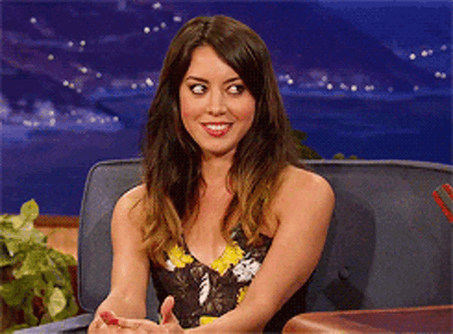 a woman is sitting on a couch with her hands folded and smiling