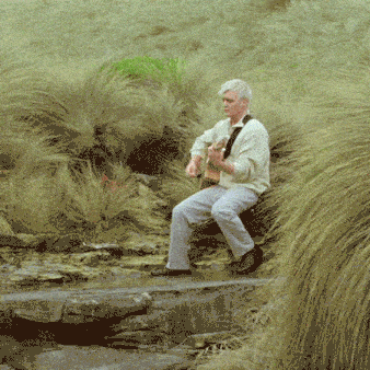 a man is sitting on a rock playing a guitar