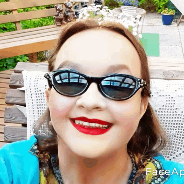 a woman wearing sunglasses and red lipstick is smiling with faceapp written on the bottom right