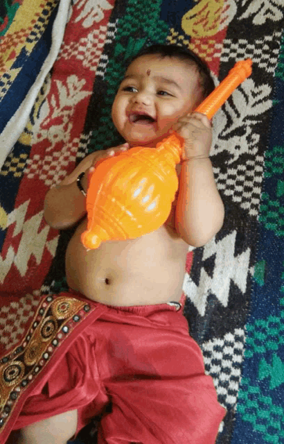 a baby laying on a blanket with a toy in his hand