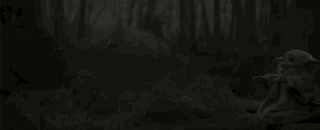 a baby yoda is sitting on a rock in the dark