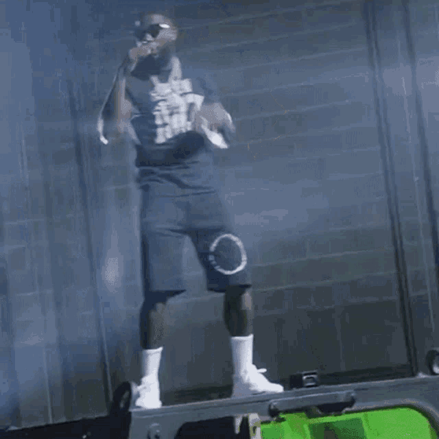 a man wearing a t-shirt that says n.y.c. is standing on a green ladder