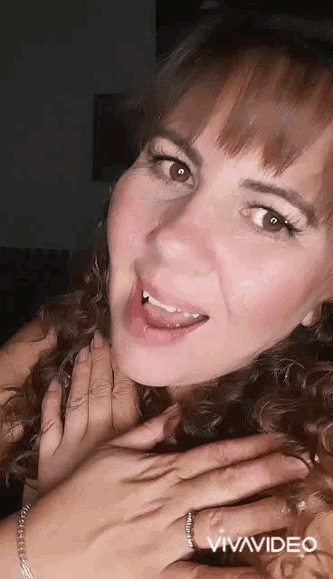 a close up of a woman 's face with her hands on her neck .