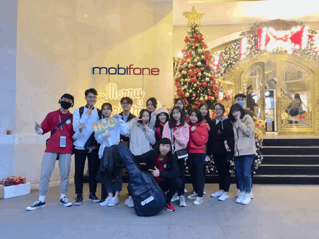 a group of people are posing in front of a mobifone sign