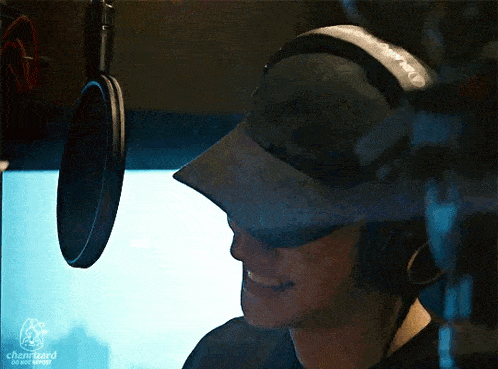 a man wearing a hat and headphones is smiling in front of a microphone that says chanwizard on the bottom right