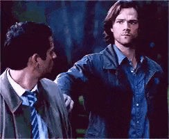 two men are standing next to each other in a dark room .