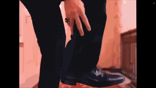 a man wearing a ring on his finger is putting on his shoes