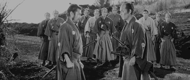 a black and white photo of a group of men in kimonos holding swords