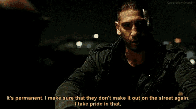 a man is sitting in a dark room talking to another man .