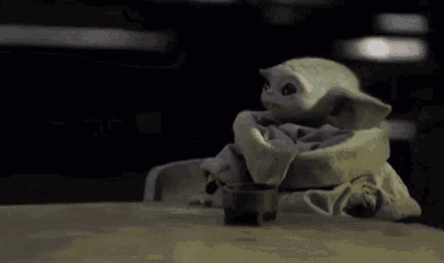 a baby yoda is sitting at a table with a tray of mcdonald 's food in the background .