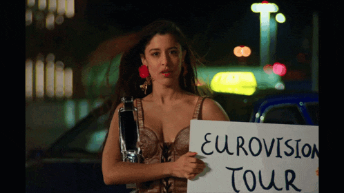 a woman holding a sign that says eurovision tour on it