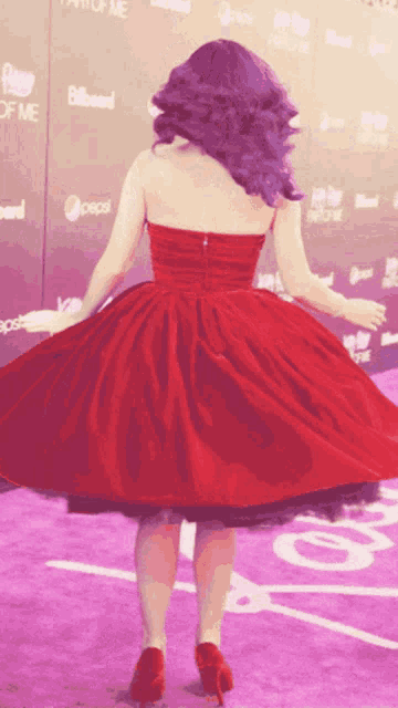 a woman in a red dress is dancing on a purple carpet in front of a billboard that says pepsi