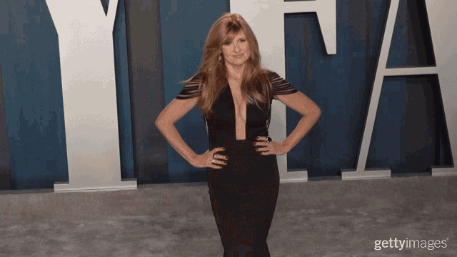 a woman in a black dress stands with her hands on her hips in front of a large letter y