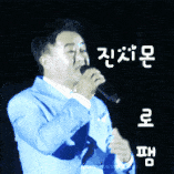 a man in a blue suit singing into a microphone with chinese writing behind him