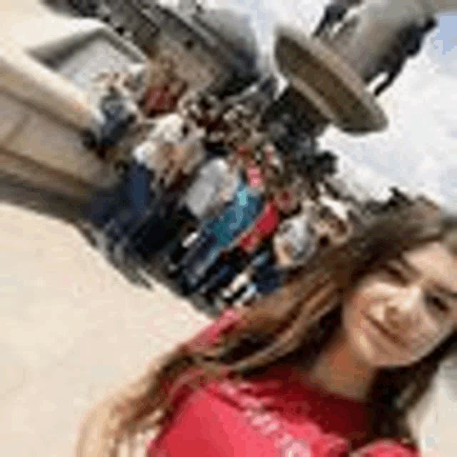 a woman in a red shirt is taking a selfie in front of a statue of a horse .