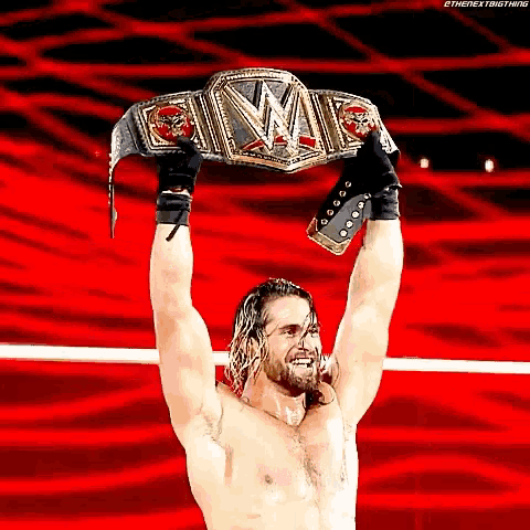 a shirtless wrestler is holding up a wrestling championship belt