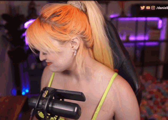 a woman with orange hair is sitting in front of a microphone with a watermark that says / danielle