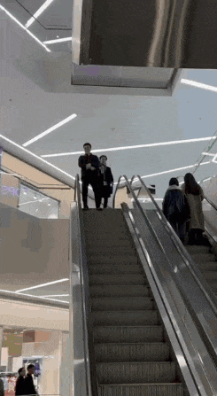 a group of people riding an escalator in a shopping mall