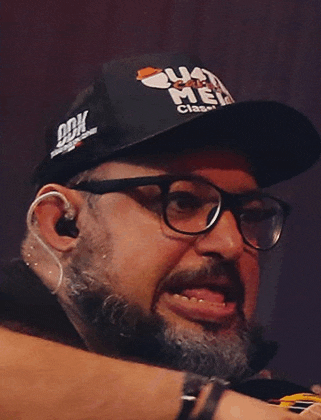 a man with a beard and glasses wears a black hat that says ' ua ' on it