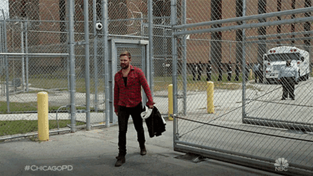 a man in a red plaid shirt is walking through a fence with #chicagopd on it