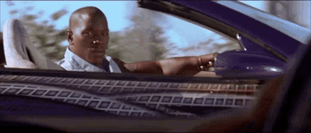 a man is driving a purple car with a checkered pattern on the seats