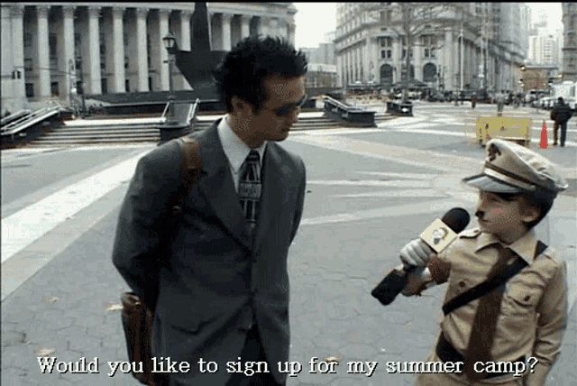 a man in a suit and tie is talking to a little boy in a costume