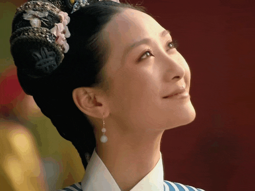 a close up of a woman 's face with a flower in her hair and earrings