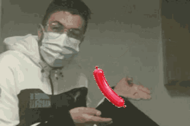 a man wearing a mask and glasses is holding a red pepper