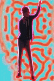 a man in a suit and tie is dancing in front of a colorful pattern